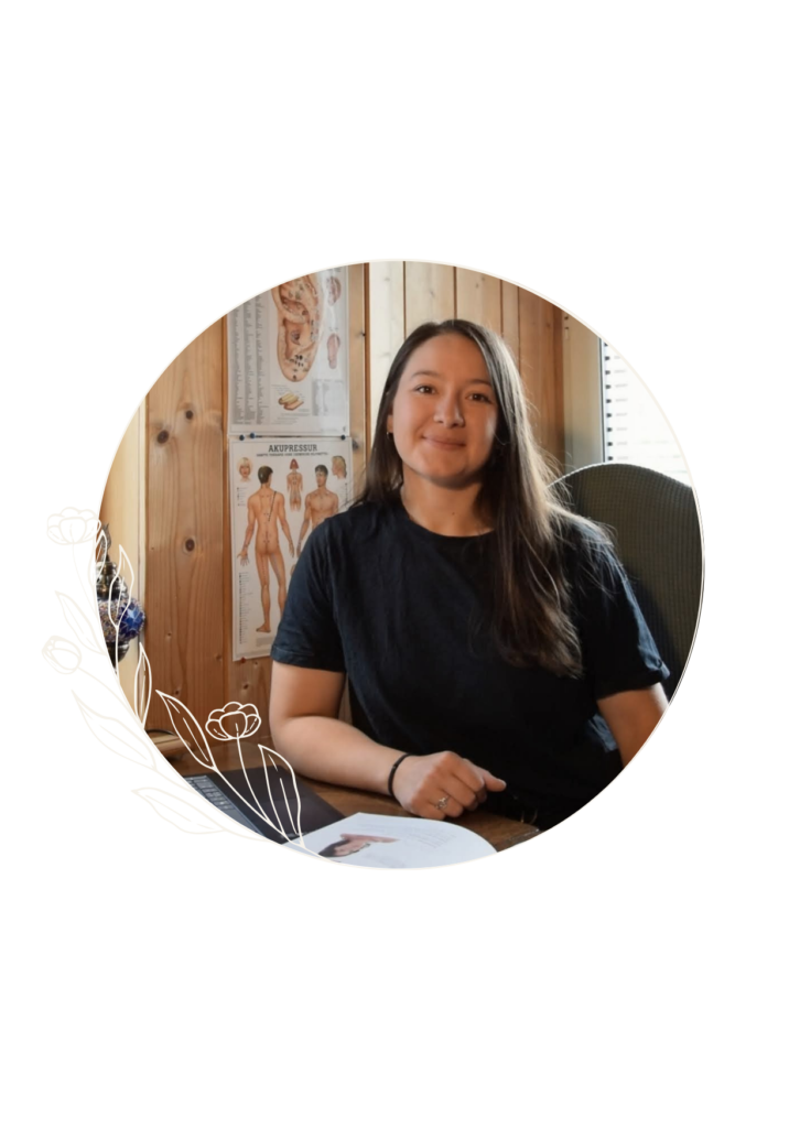 Tessy Perez Praticienne en Energétique Traditionnelle Chinoise, assise à son bureau avecdes posters de méridiens en fond.